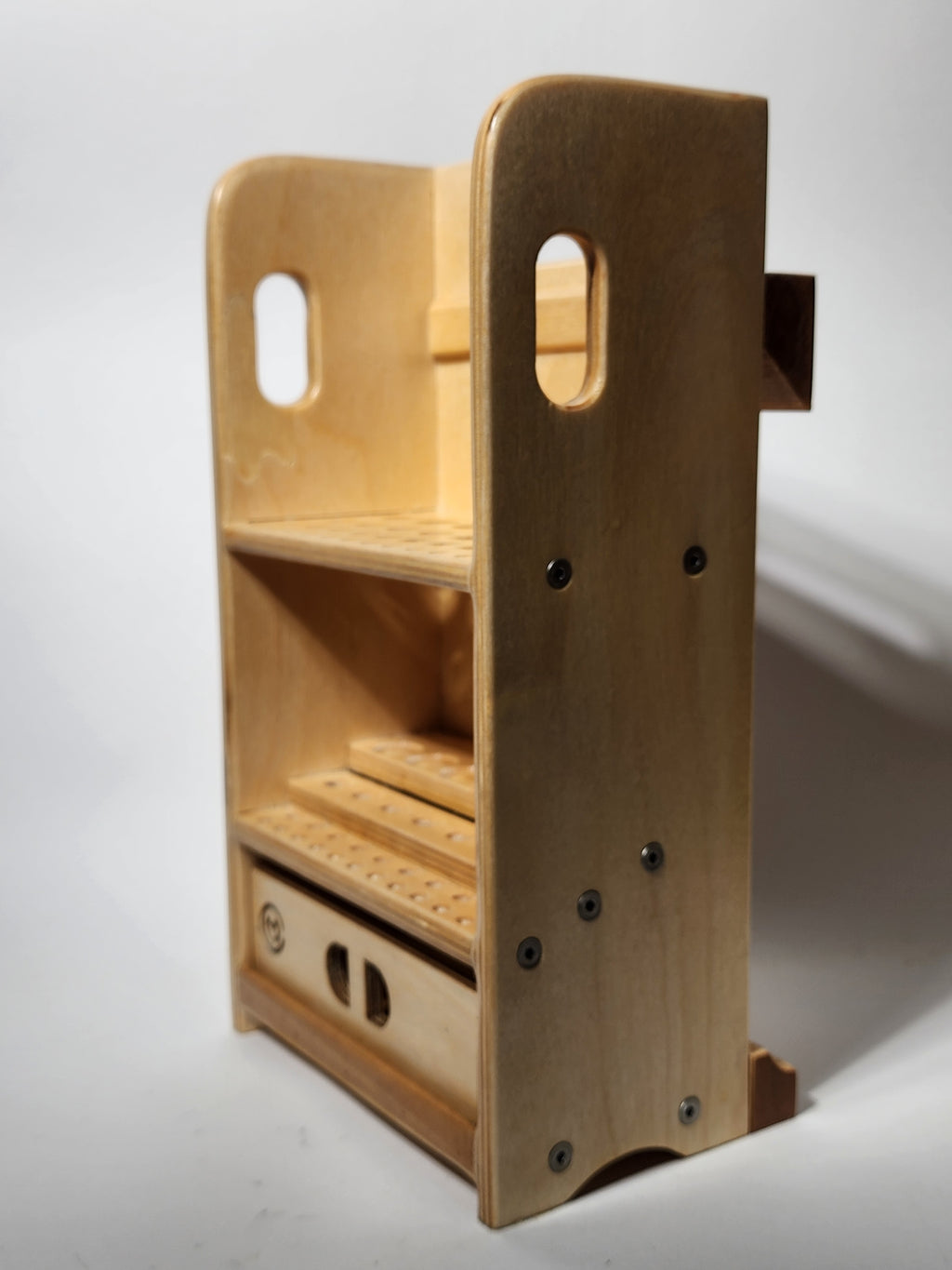 Angled side view of the El Compañero™ Small General Tool Organizer, a handcrafted wooden caddy with integrated carry handle openings, exposed layered wood edges, vertical drilled tool storage, a stepped interior layout, CUSTOMadera branding, and a lower sliding drawer for small accessories or workshop supplies.