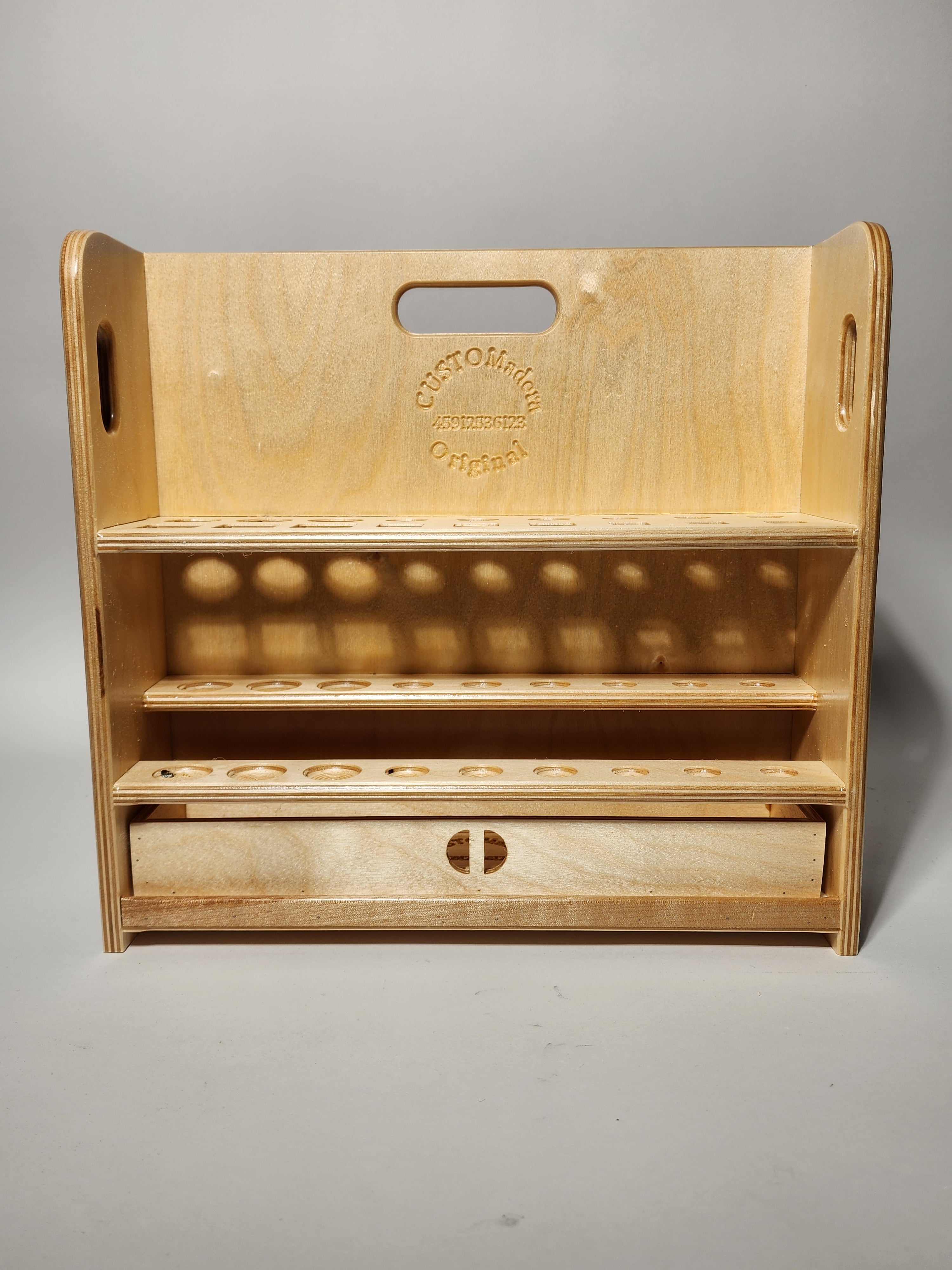 Front view of the El Pilar™ Large General Tool Organizer, a handcrafted wooden caddy with vertical tool storage, stepped shelves, integrated carry handle openings, CUSTOMadera branding, and a lower drawer for organized workshop storage.