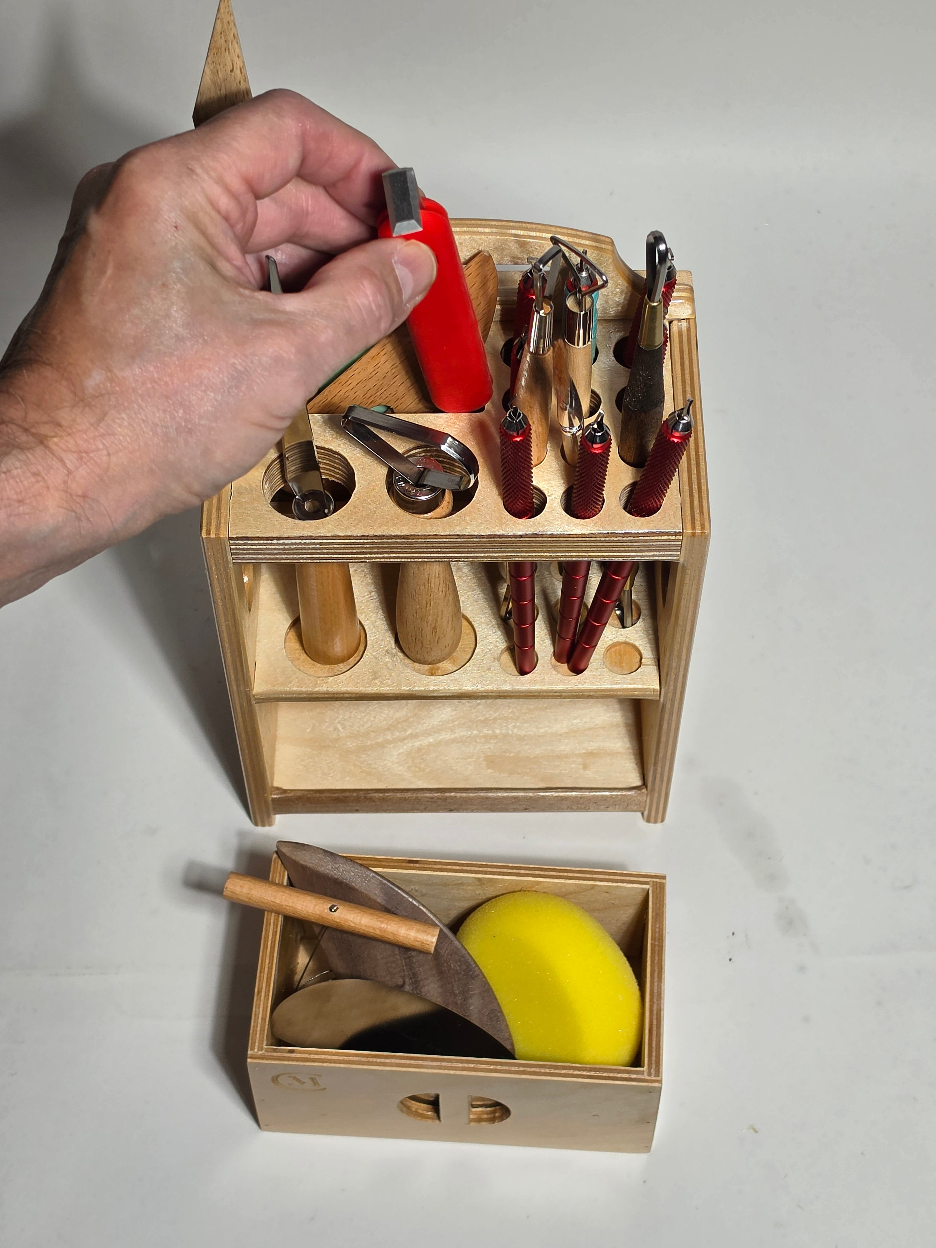 Top view of the La Forma™ wooden pottery tool organizer with ceramic tools stored upright and an open drawer holding ribs, a sponge, and finishing tools.
