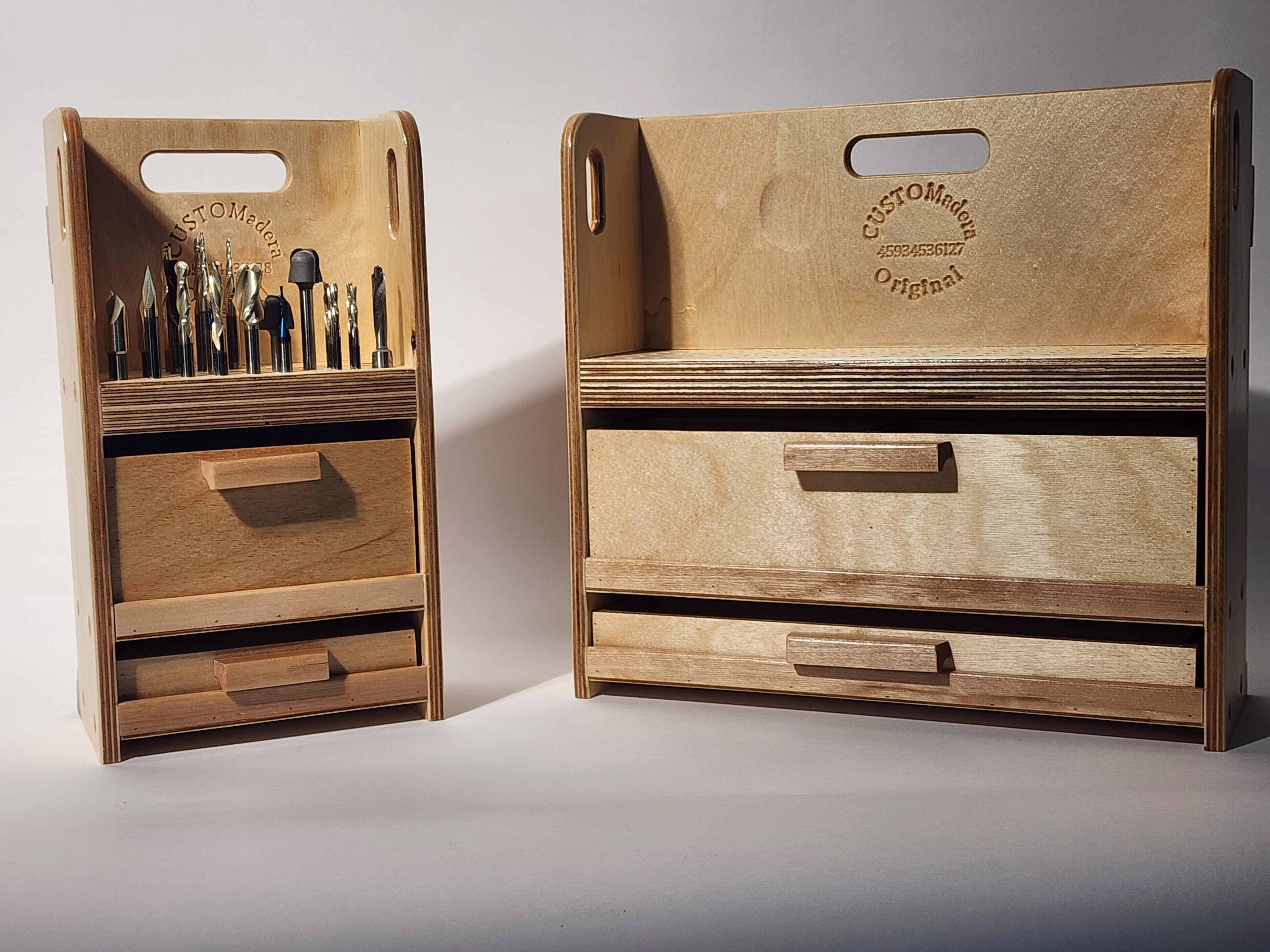Side-by-side view of a large CNC bit organizer and a small CNC bit organizer, shown together to compare size, storage capacity, drawer layout, vertical bit storage, integrated carry handles, and handcrafted wooden construction. Products are shown together for size comparison only and are sold separately.